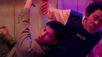 Marry My Dead Body movie: Taiwanese man in tan jacket center and Taiwanese police man in police vest right are sitting down both handcuffed to a bar rail 