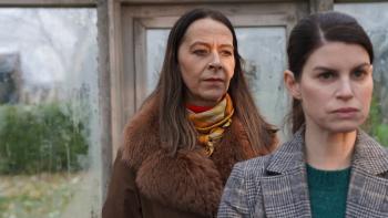 Two tense-looking women from middle distance, one with her back to the other.