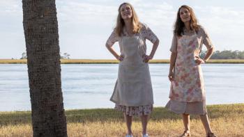 May December Movie: Julianne Moore and Natalie Portman, wearing aprons, stand outside in front of a lake, looking up