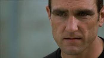 Mean Machine: Close-up of a stern-looking man with short dark hair wearing a black top, with an intense or troubled expression on his face