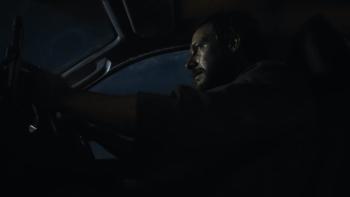 Mercy Road: A side view of a dishevelled, bearded White many driving in a car.