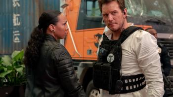 Mercy movie: Kali Reis and Chris Pratt (wearing a bulletproof vest and earpiece) share their suspicions while standing near a truck