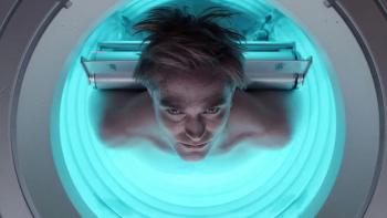 Mickey 17 Movie: Mickey (Robert Pattinson) stands in a large metal tube full of blue light