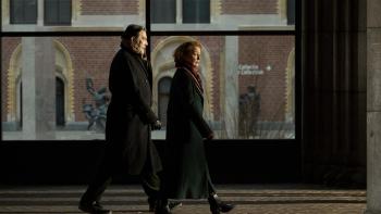 Midwinter Break movie photo of a married man and woman walking side by side with coats on in Amsterdam.