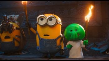 Minions & Monsters movie: A minion holds a torch next to a green creature