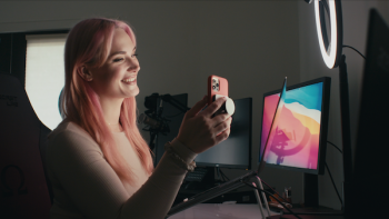 Still from Money Shot: The Pornhub Story: Siri Dahl, who is White and is identified as a porn performer, has a smartphone conversation with a client, wearing a pale pink top that matches her hair of a similar color