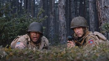 Murder Company movie: Pooch Hall and William Moseley lie behind a bunker, aiming to shoot someting