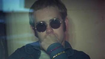 Elton John -- Never Too Late: A younger Elton John wearing sunglasses with his hand to his mouth