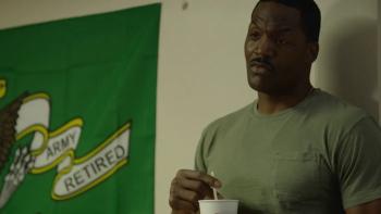My Brother's Keeper Movie: A Black man in a green T-shirt stirs coffee while standing by a sign that says "Army Retired"