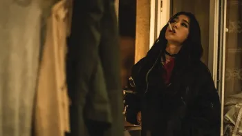 My Name is Loh Kiwan movie: Korean woman with long black hair in black jacket right looks upwards with cigarette in her mouth