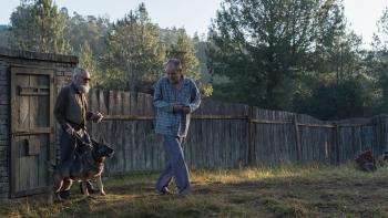 My Neighbor, Adolf: An elderly White man with a beard walks with a dog on a lead, with another elderly White man in front of him in a garden