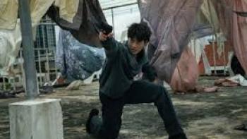 My Dearest Assassin: Man in action pose, crouching with arm extended on a rooftop with laundry hanging.