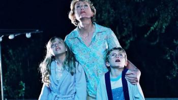 Mysterious Skin Movie: Woman and two children gazing at the night sky, wearing pajamas, with trees in the background.