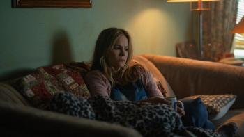 Night Always Comes: A middle-aged woman sits on a sofa looking concerned