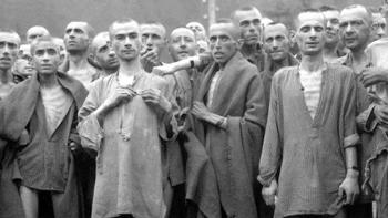 Night and Fog: A group of men stand huddled together, imprisoned in a concentration camp