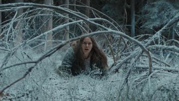 Nightborn: A young White woman crawling through snowy forest, branches overhead