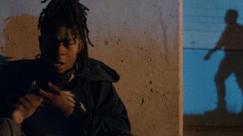 Night Patrol Movie: Wazi (RJ Cyler) hides up against a concrete wall while a sinister shadow appears to stalk him