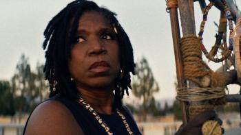 Night Patrol Movie: Ayanda (Nicki Micheaux) looks up from one of her Zulu totems with a wary look on her face.