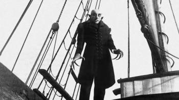 Max Schreck towers up from the deck of a boat, his figure in silhouette against the sky in Nosferatu: A Symphony of Horror