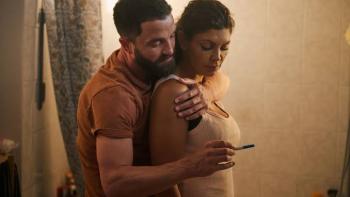 Nothing to Lose movie: Man hugging woman holding pregnancy test in bathroom.