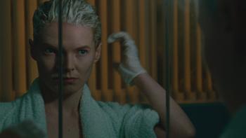 Blue Jean: A young White woman looks in the mirror while dyeing her hair