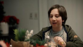 Dog Patrol: Operation Santa Paws movie: A child with dark brown hair smiles at a kitchen table