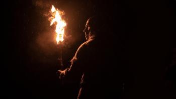 Out of Darkness Movie: Adem (Chuku Modu), in the dark and rain, holds a torch and looks to the left, a fearful expression on his face