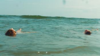 Over/Under: Two girls floating in a calm ocean under a clear sky
