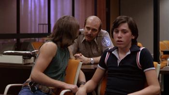 Over the Edge: A young man turns to talk to a police officer as his friend sits beside him in a police station
