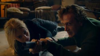 Over Your Dead Body movie: Samara Weaving and Jason Segel, lying on the floor, hold a shotgun and fight for control of it