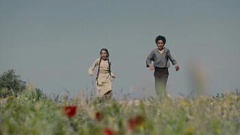 Palestine 36: Two children run together through a field