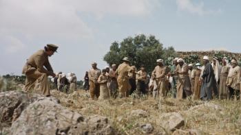 Palestine 36: A British soldier leans against a rock formation as other British soldiers hold Arab men and boys captive, with their hands tied