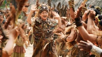 Panda Plan 2: The Magical Tribe Movie: Jackie Chan, dressed up in tribal gear, holds his hands up as he happily dances