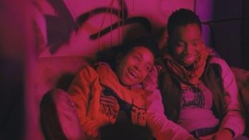 Pariah Movie Poster: Two people on a couch, laughing under pink lighting.