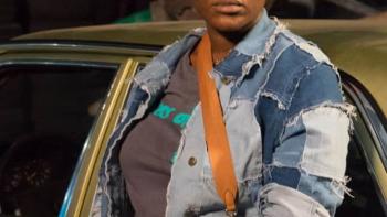 Passport: Nigerian woman in jean jacket has shoulder purse and stands in front of car