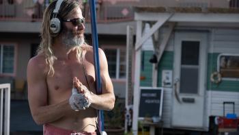Poolman Movie: Shirtless Darren wears sunglasses and CD Walkman headphones while holding his pool-scooper
