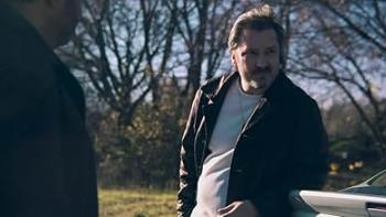 Porch Pirates movie: A Latino American man left talks with a White man center next to the trunk of a car while outside 