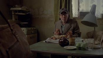 Possum: An old White man sits at the table in a run-down kitchen holding a puppet