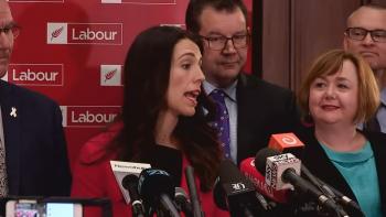 Prime Minister movie: Jacinda Ardern addresses her nation of New Zealand at a press conference, White New Zealander men and women in suits behind her