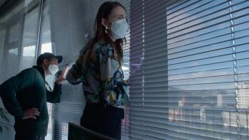 Prime Minister movie: Jacinda Ardern center and Clarke Gayford left look through window blinds at protestors below them