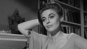 The Pumpkin Eater: Anna Bancroft leans her elbow on a fireplace mantel, a wry smile on her face