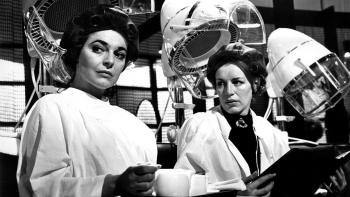 The Pumpkin Eater: Anne Bancroft sits in a chair at a hair salon, a woman looking at her intensely to her left