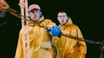 Rose of Nevada: Two fishermen in yellow raincoats on a boat, one holds a chain