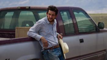 Rebuilding movie: Dusty Fraser (Josh O'Connor) leans against a truck, his hat in his hand