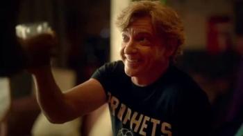 Relax, I'm from the Future: Rhys Darby raises a glass wearing a blue shirt