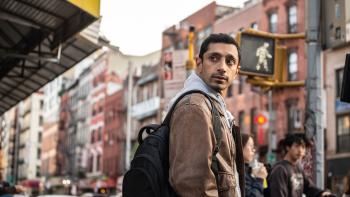 Relay movie: Riz Ahmed looks over his shoulder while wearing a backpack in New York
