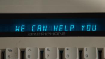 Relay movie: Close-up of a 1970s-era Ameriphone sceen above a typewriter saying "We Can Help You"