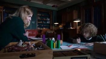 Marionette: Dr. Marianne Winter and Elijah Wolf sit at opposite sides of a desk as he draws a picture.