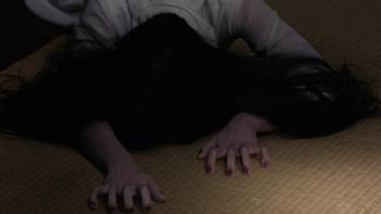 The Ring: A ghostly figure in a white dress with long hair crawls along the floor with their face hidden