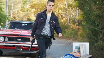 Riot Girls Movie: Scratch walks away from a red muscle car with a handgun